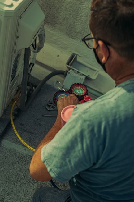 Technician checking refrigerant gauges during an air conditioning maintenance visit